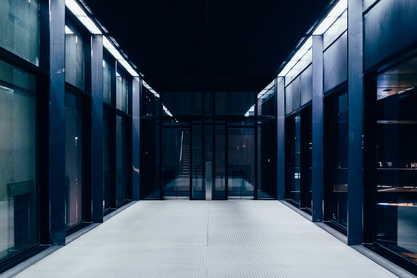 Clean data center corridor with glass-panel racks extending to vanishing point